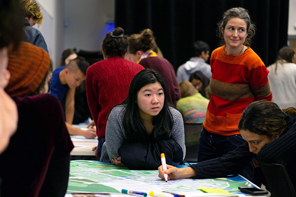 Three female students gather around a table at the workshop.