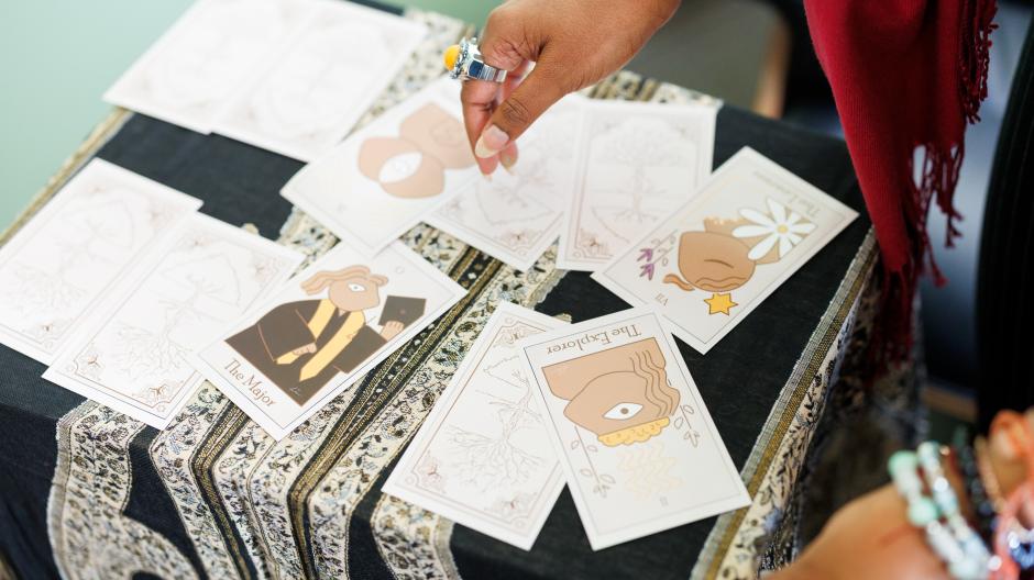 A pair of hands arranging an assortment of tarot cards on a small table.