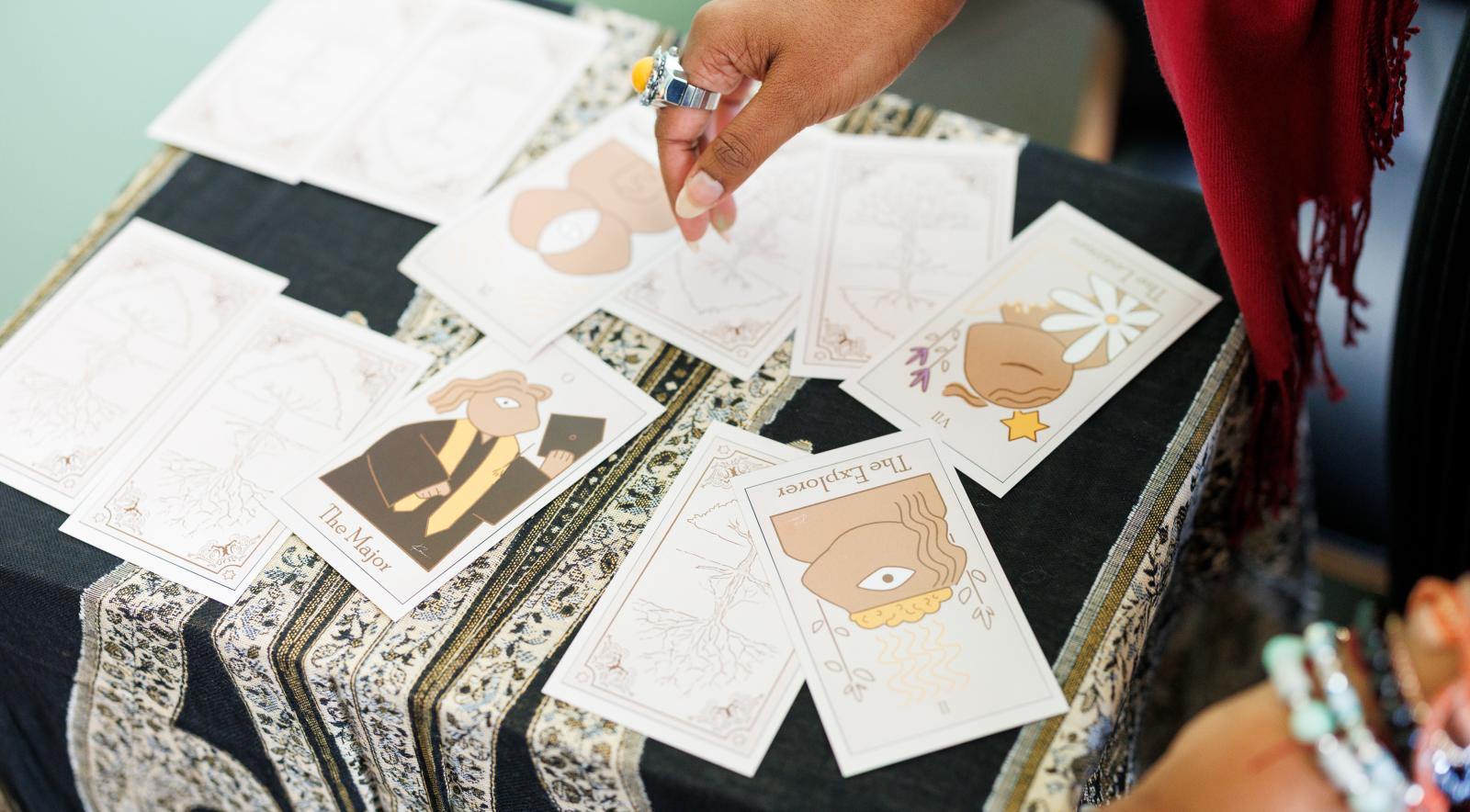 A pair of hands arranging an assortment of tarot cards on a small table.